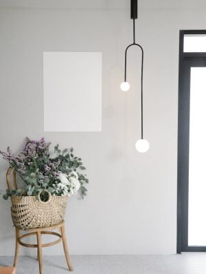 Bouquet of fresh wildflowers in wicker basket placed near wall with white mockup