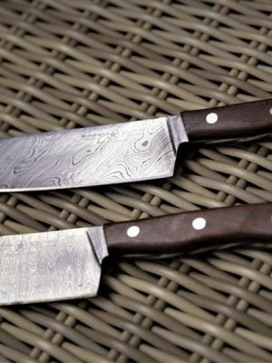 Two knives on a woven mat with a wooden handle