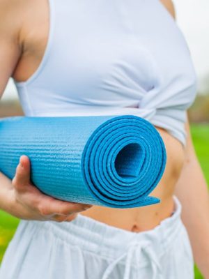 Woman Standing and Holding Blue Yoga Mat